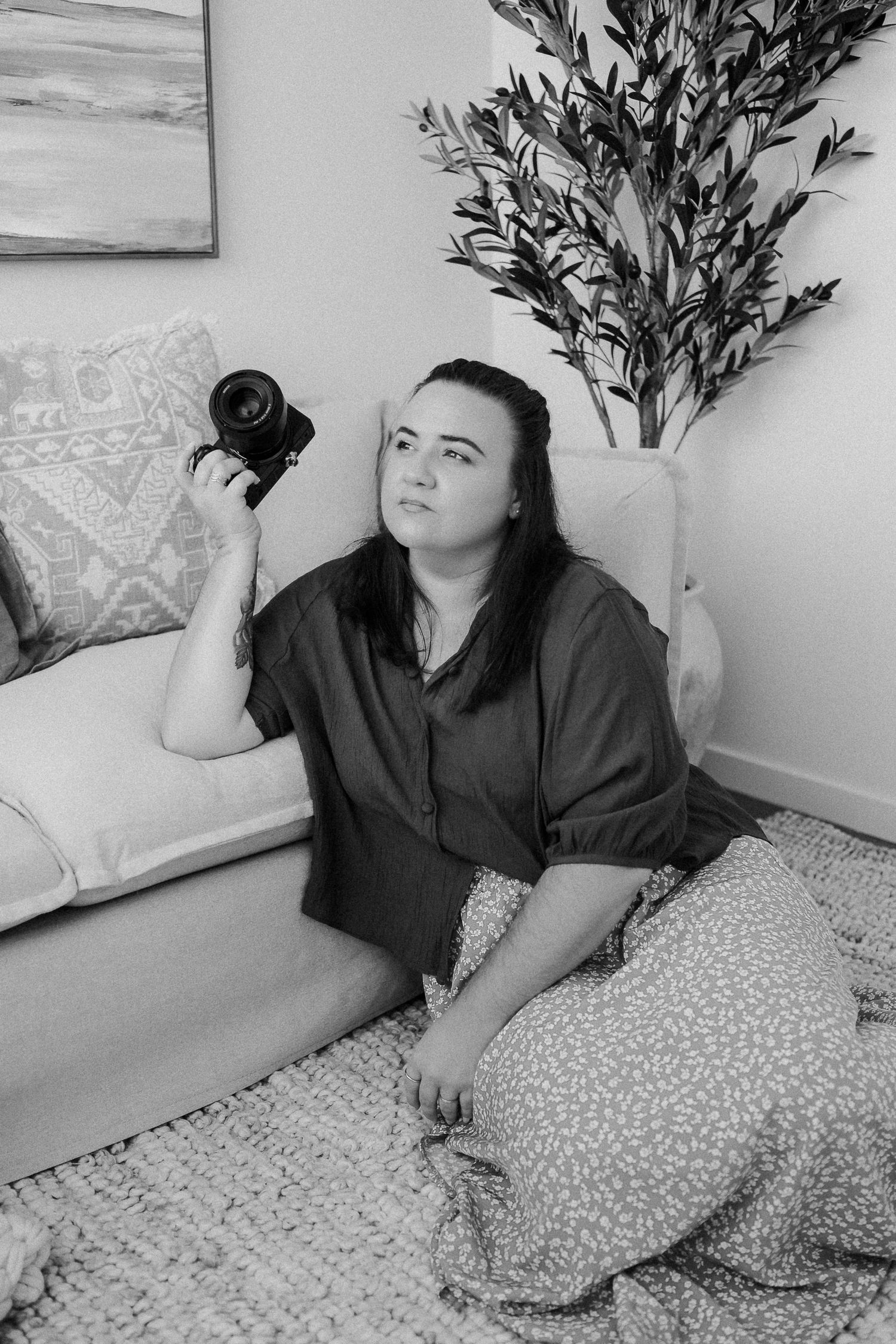 A series of black and white photos showing someone lounging on a bed with patterned pillows and a potted plant.