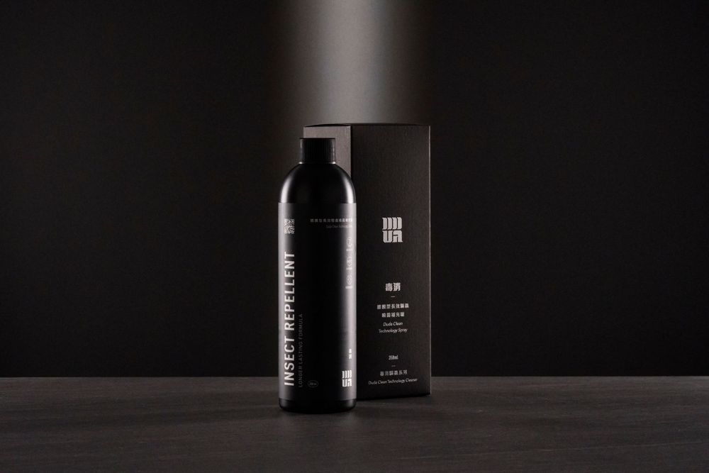Sleek black cosmetic bottle and packaging box against dark background with dramatic lighting.