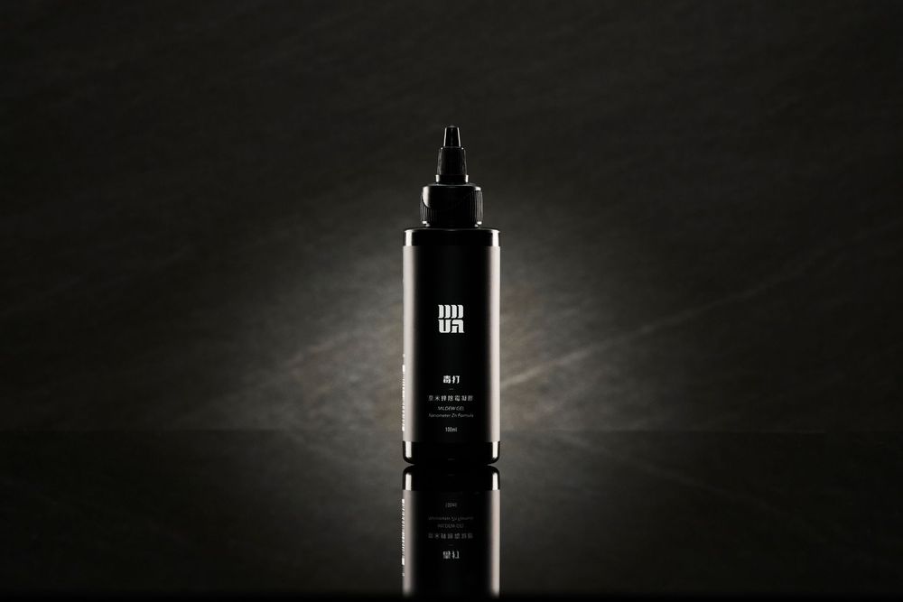Silhouette of a dark cosmetic bottle with dropper cap illuminated against a moody gray backdrop.