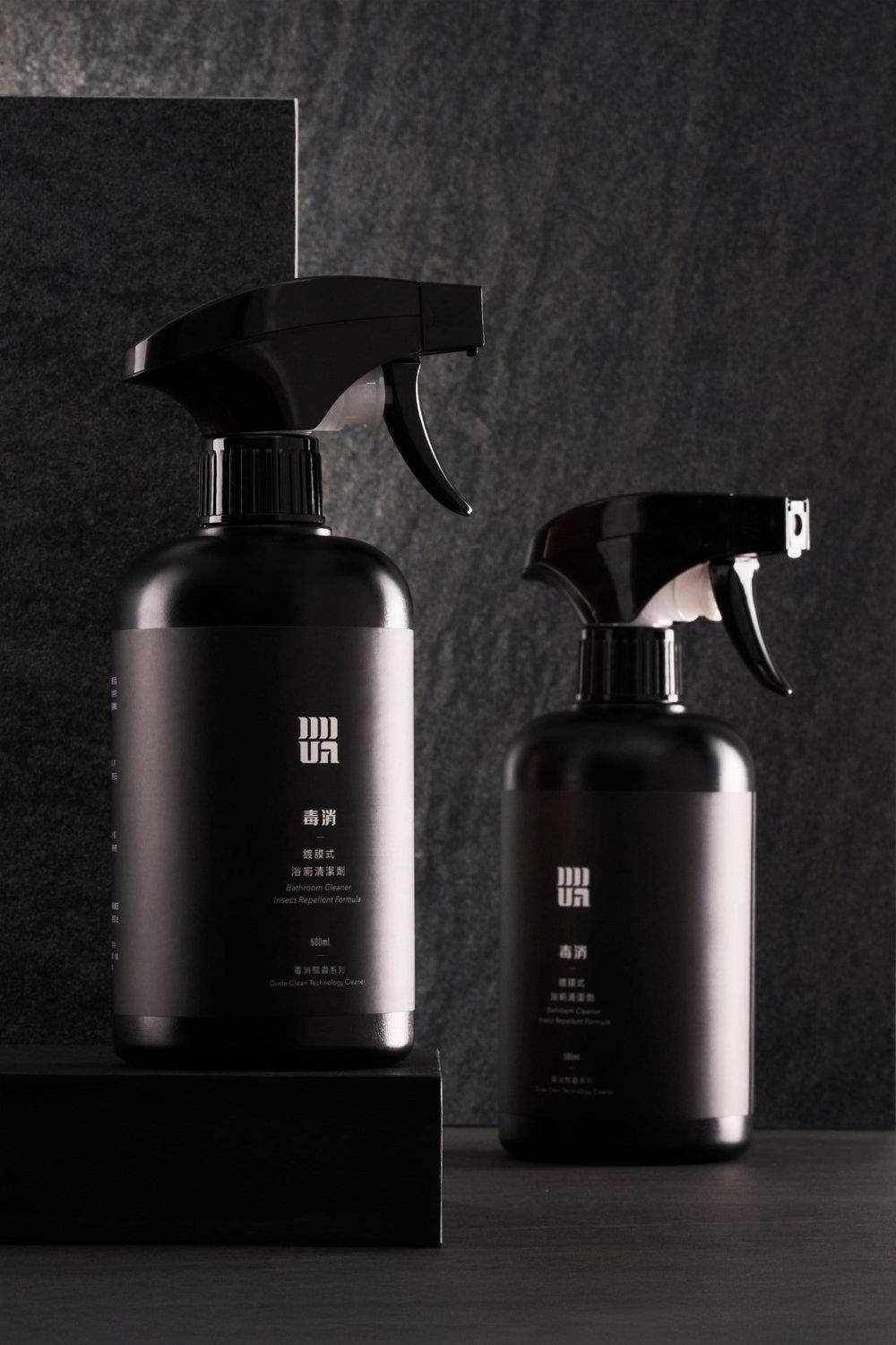 Sleek black product containers cast moody shadows on dark surface in artistic product photography.
