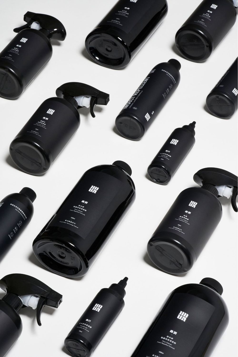 Multiple black glass bottles arranged in diagonal rows against a white background create a striking minimalist pattern.