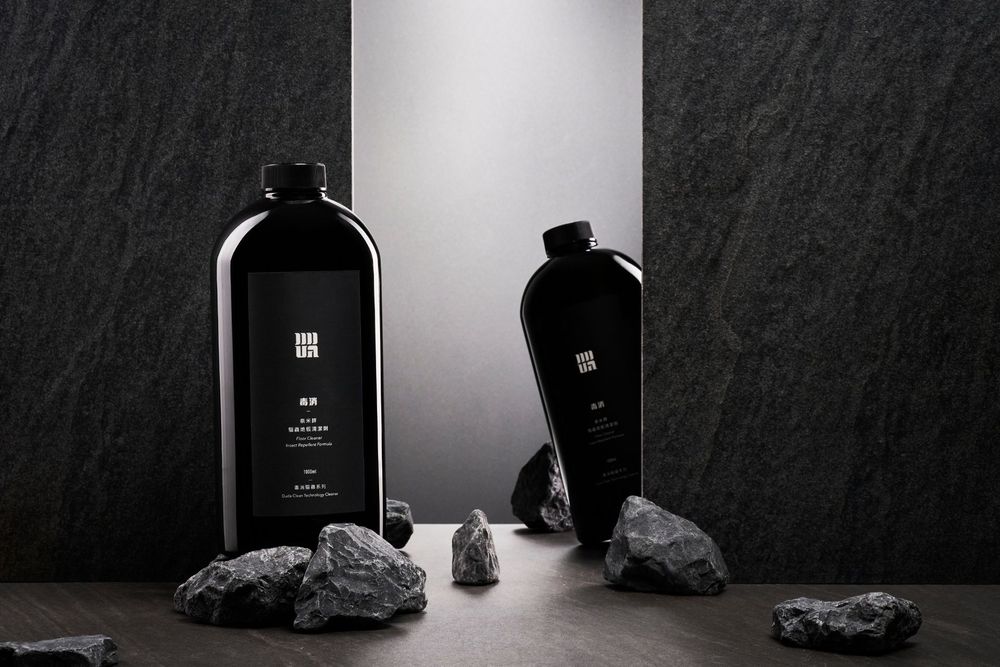 A single black glass bottle stands elegantly against a white backdrop with dramatic side lighting.