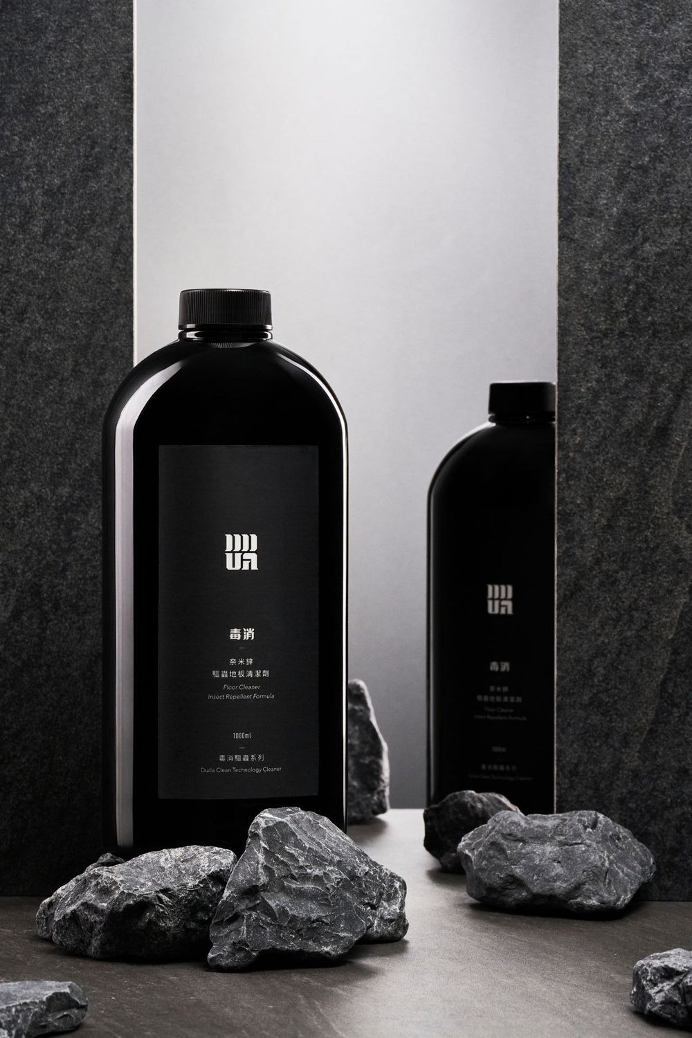 Sleek black cosmetic bottles displayed with raw coal or charcoal pieces against a monochromatic background.