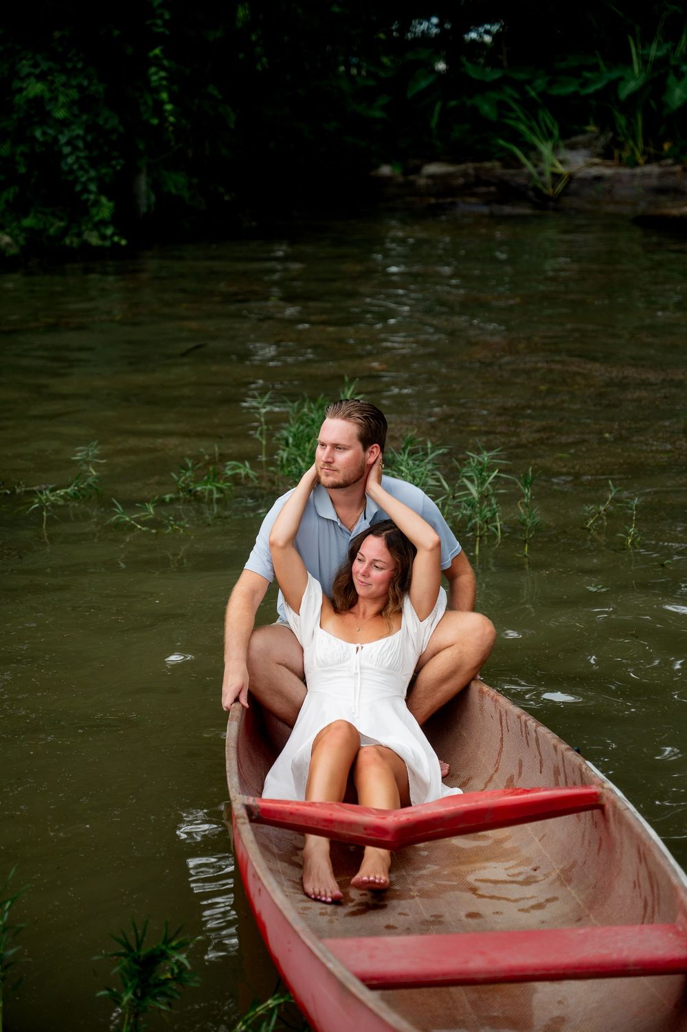 Couple relaxing in a red canoe on tranquil waters surrounded by marsh grass.