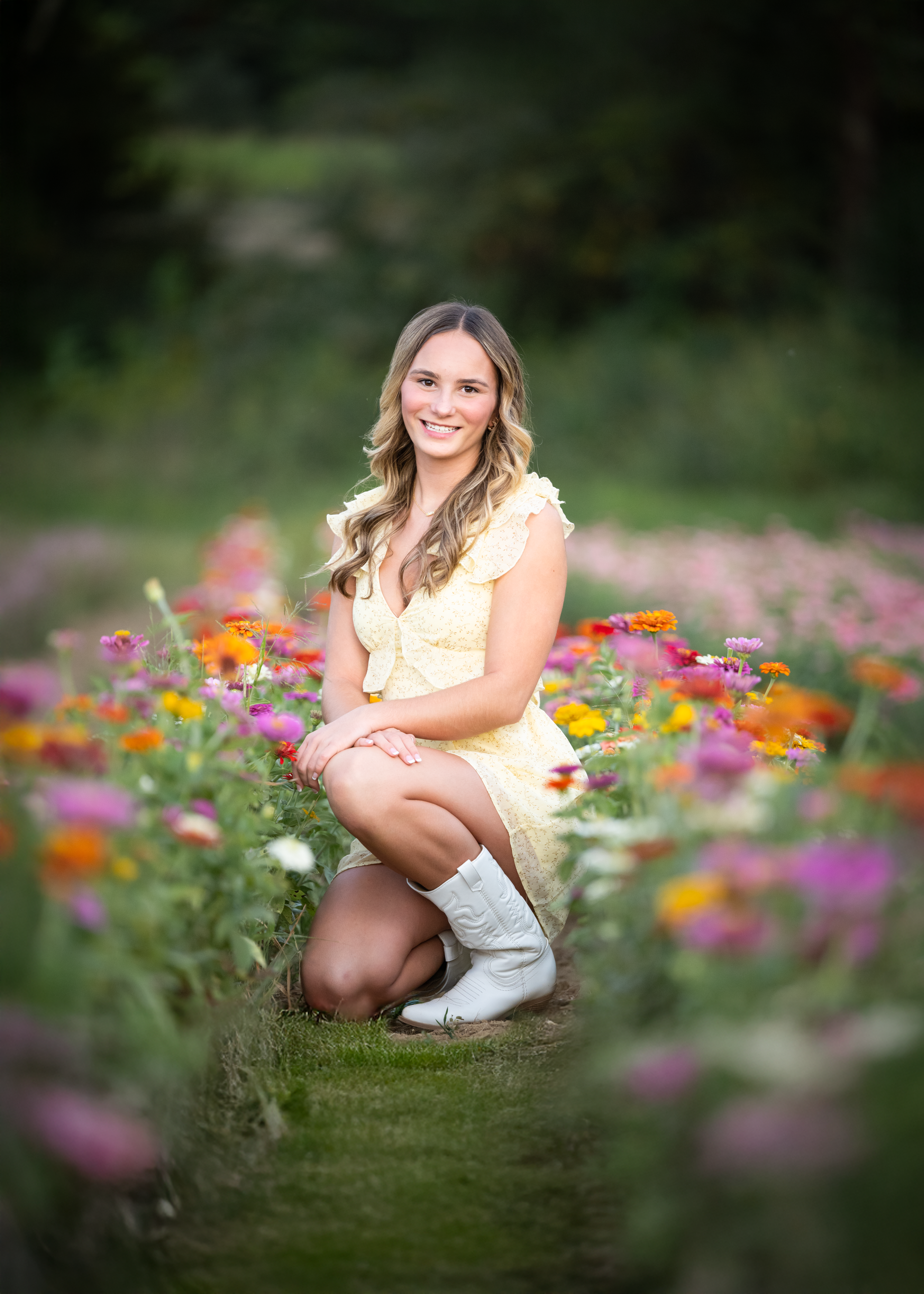 Dance photography rep Addy wears a yellow dress in a vibrant wildflower field to celebrate the end of summer with her team