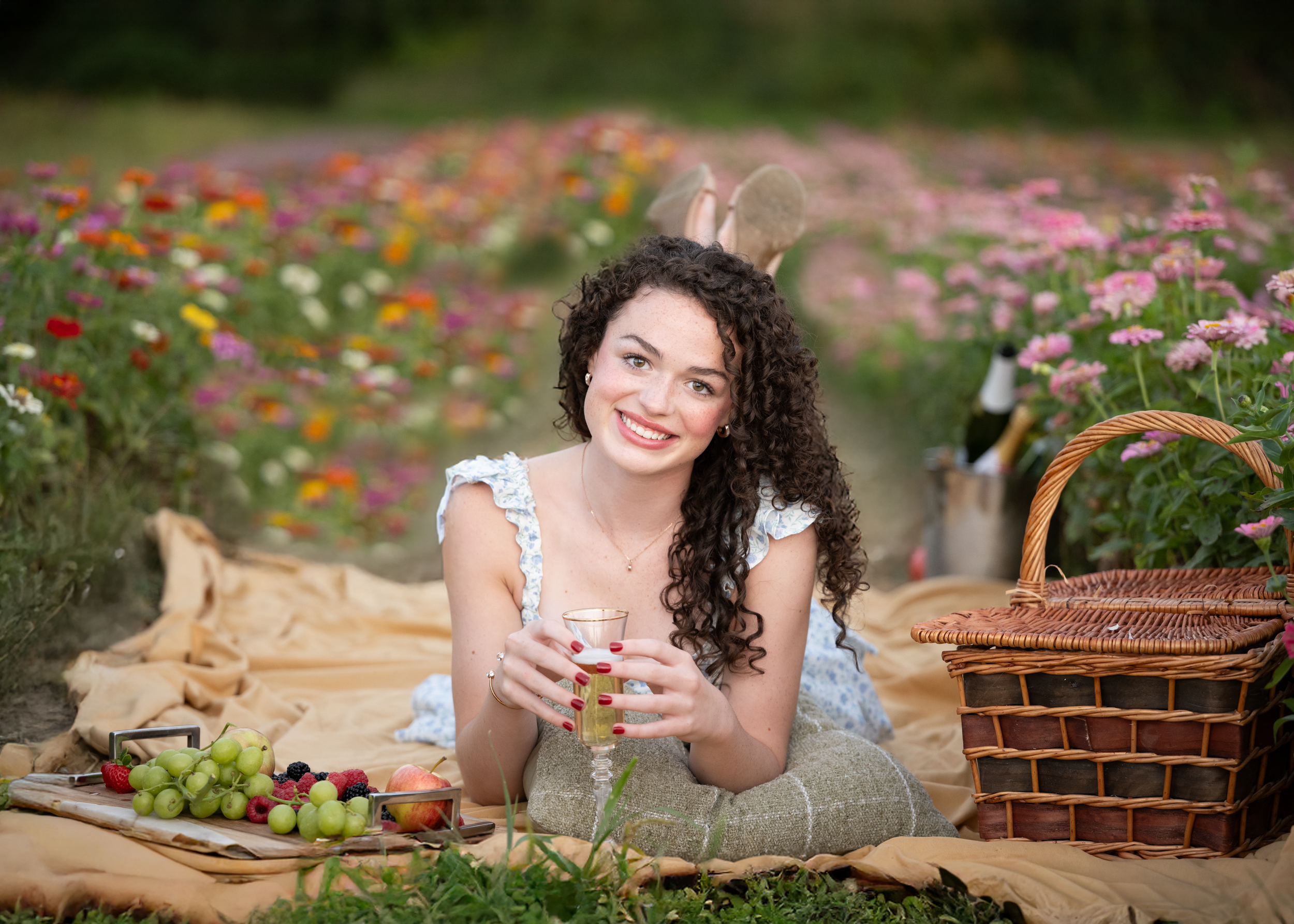 Dance photography rep Becca relaxes outdoors at golden hour surrounded by colorful wildflowers and greenery at Clover Valley Farm