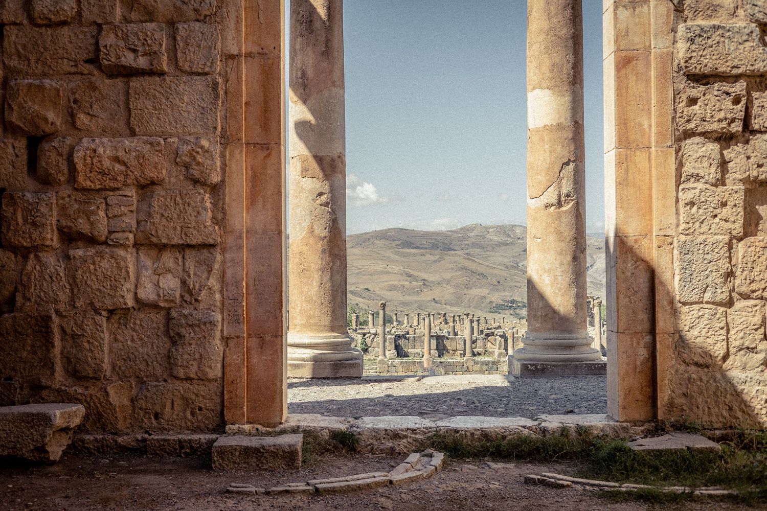 Ancient stone doorways and columns framing desert mountain views in archaeological site.