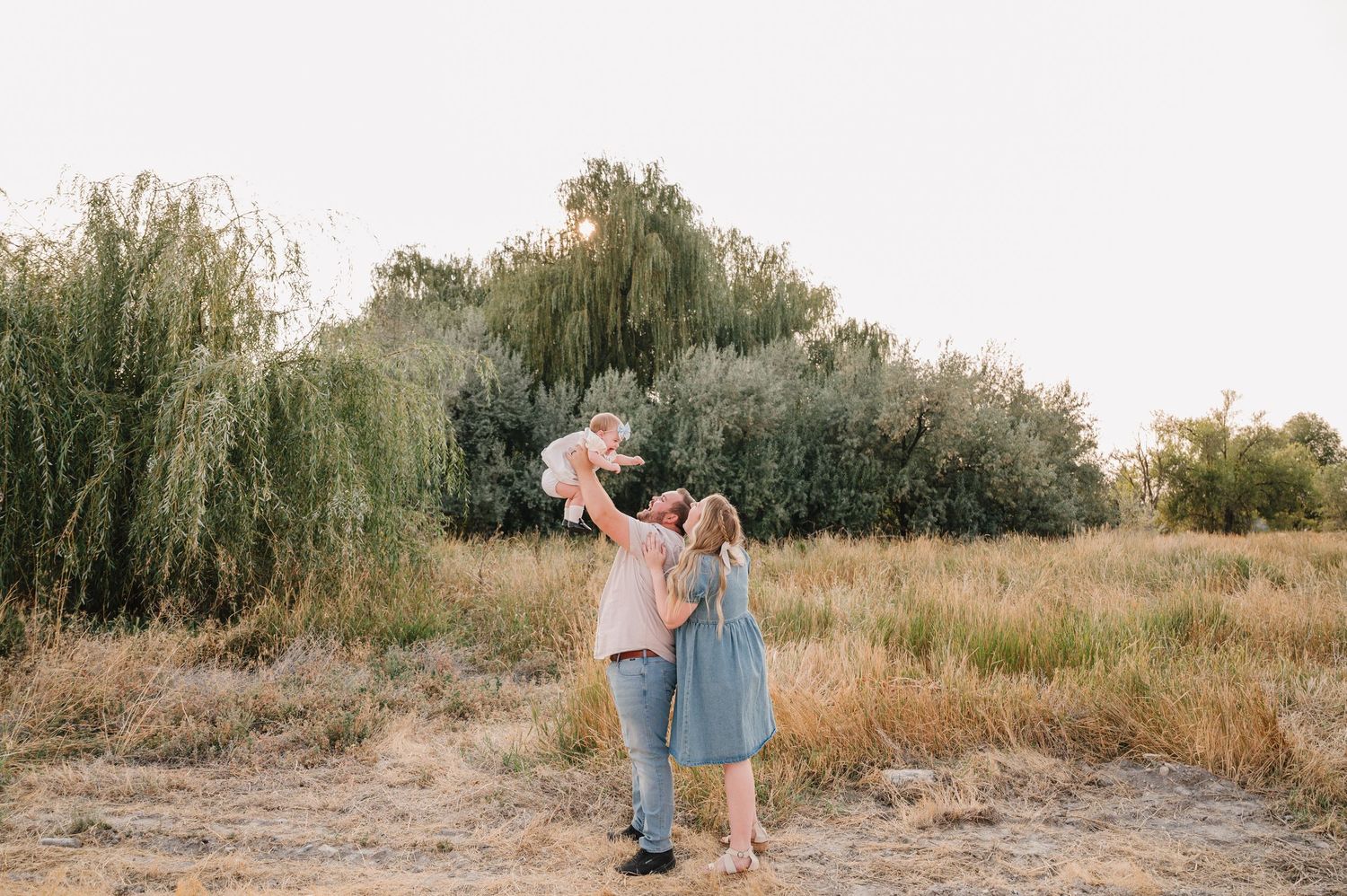 A romantic couple embraces in a golden field during sunset creating a dreamy silhouette against the warm sky.