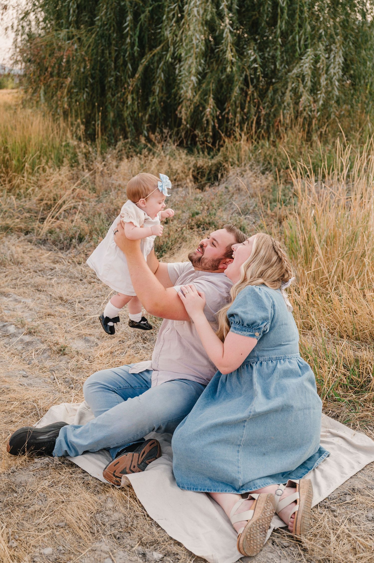A couple shares a romantic moment while relaxing on a blanket in a sun-dried field of tall grass.