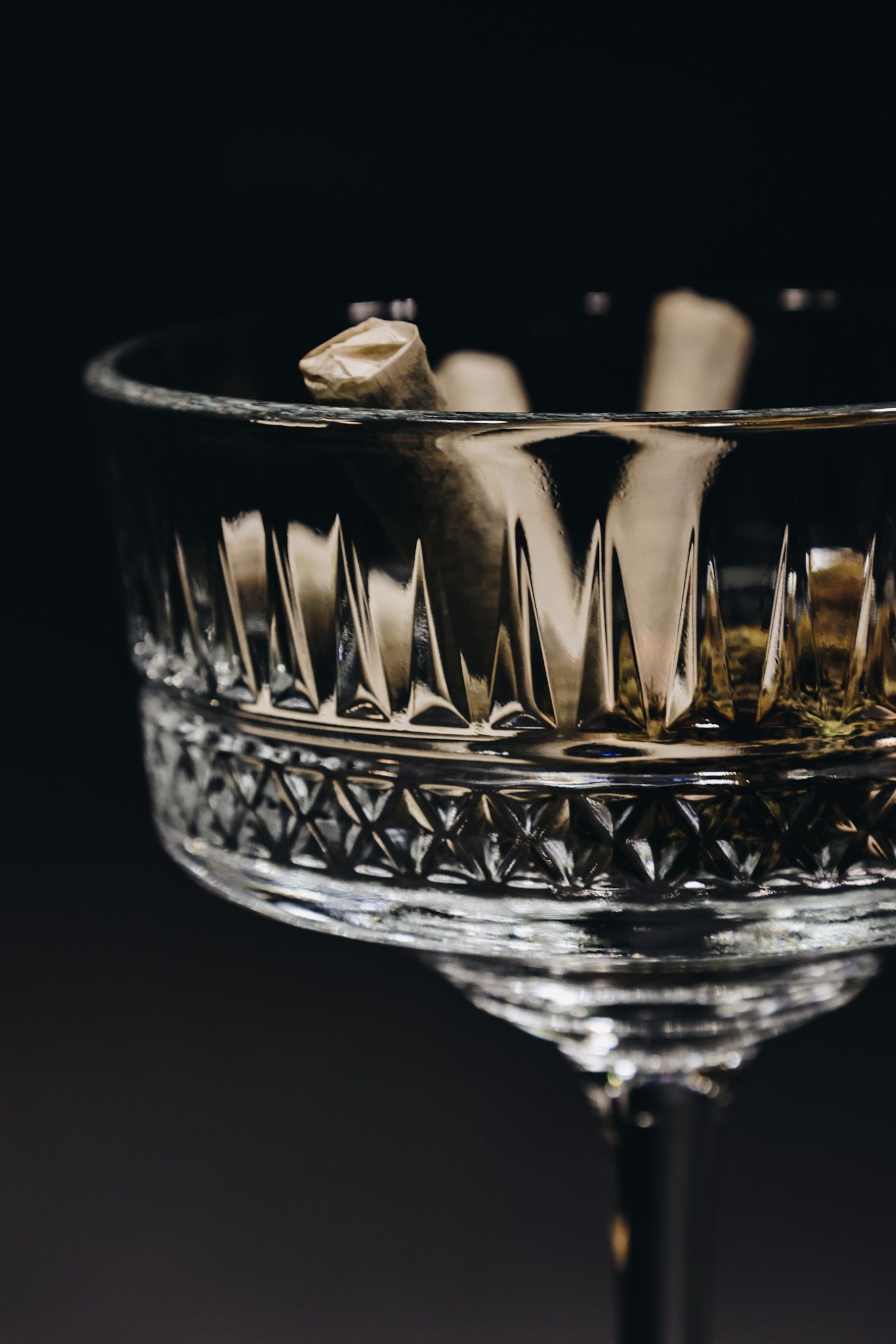 A series of close-up shots showing crystal champagne glasses with intricate geometric patterns in moody lighting.