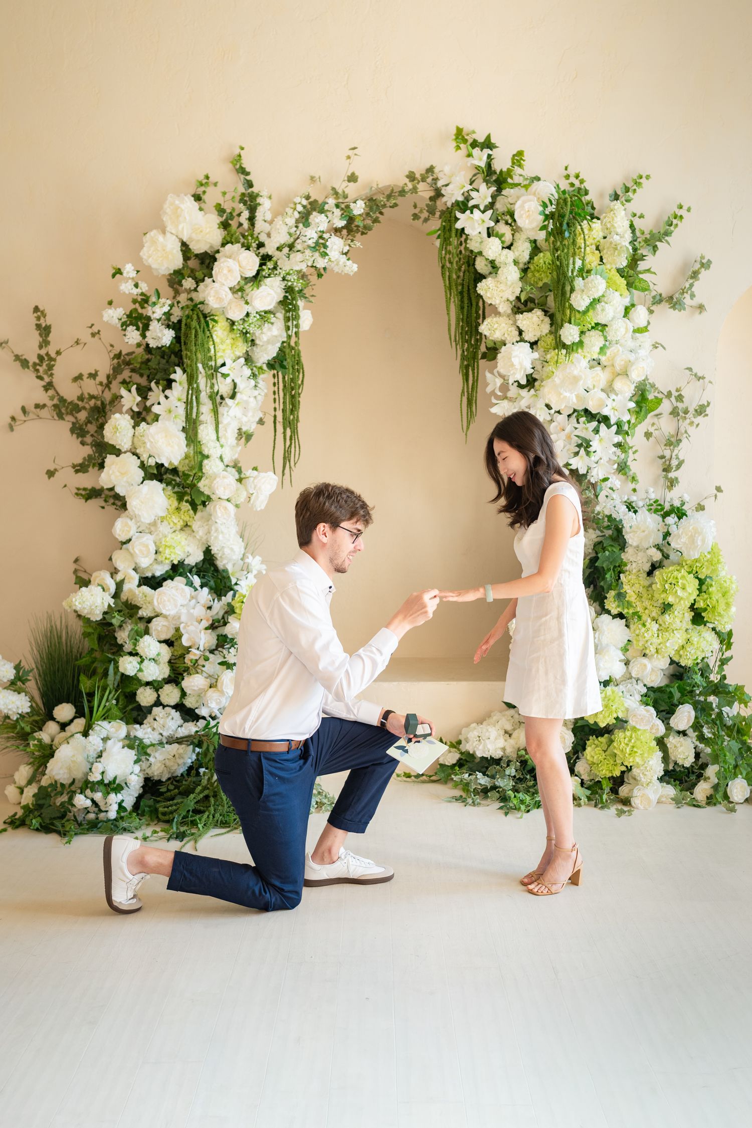 A romantic proposal sequence with white and green floral arrangements against a light backdrop showing the special moment unfold.