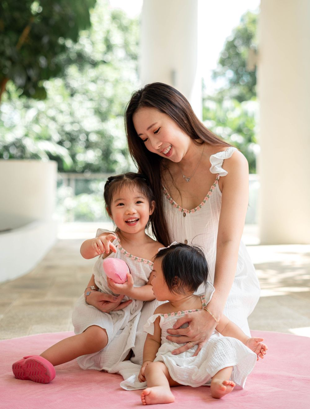 Candid family moments captured on pink blanket in natural sunlit porch setting.