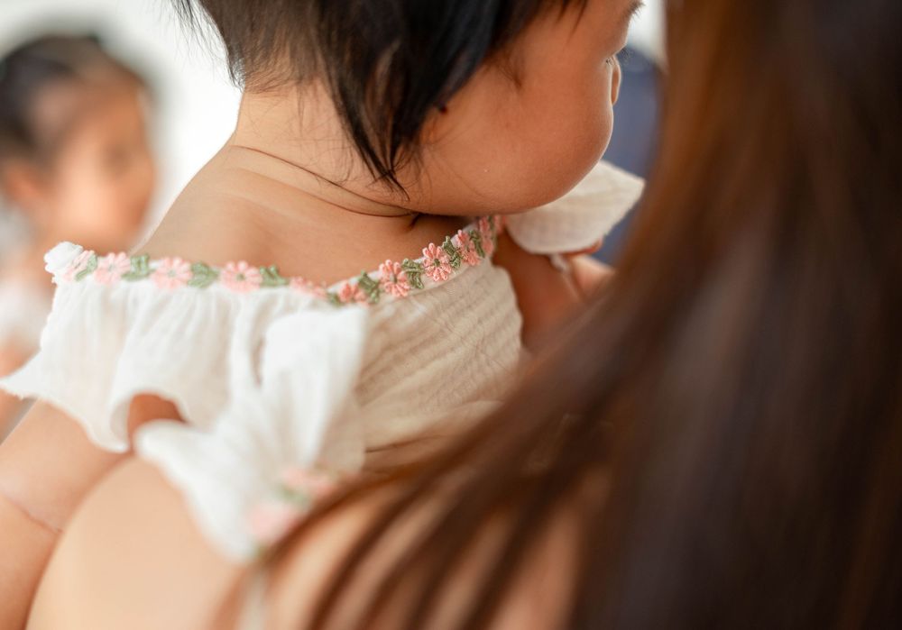 Close-up view of delicate floral embroidery detail on a white dress neckline.