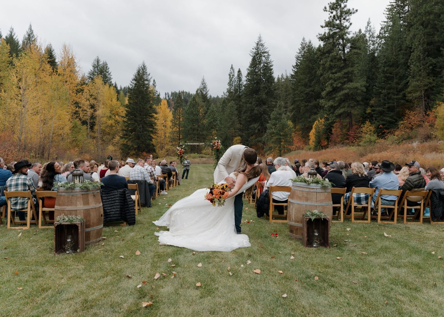 A romantic outdoor autumn wedding ceremony in a mountain meadow surrounded by evergreen trees and golden aspen leaves.