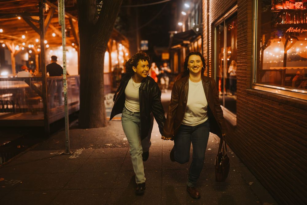 a lesbian couple walking together on dimly lit city streets at night in Seattle.