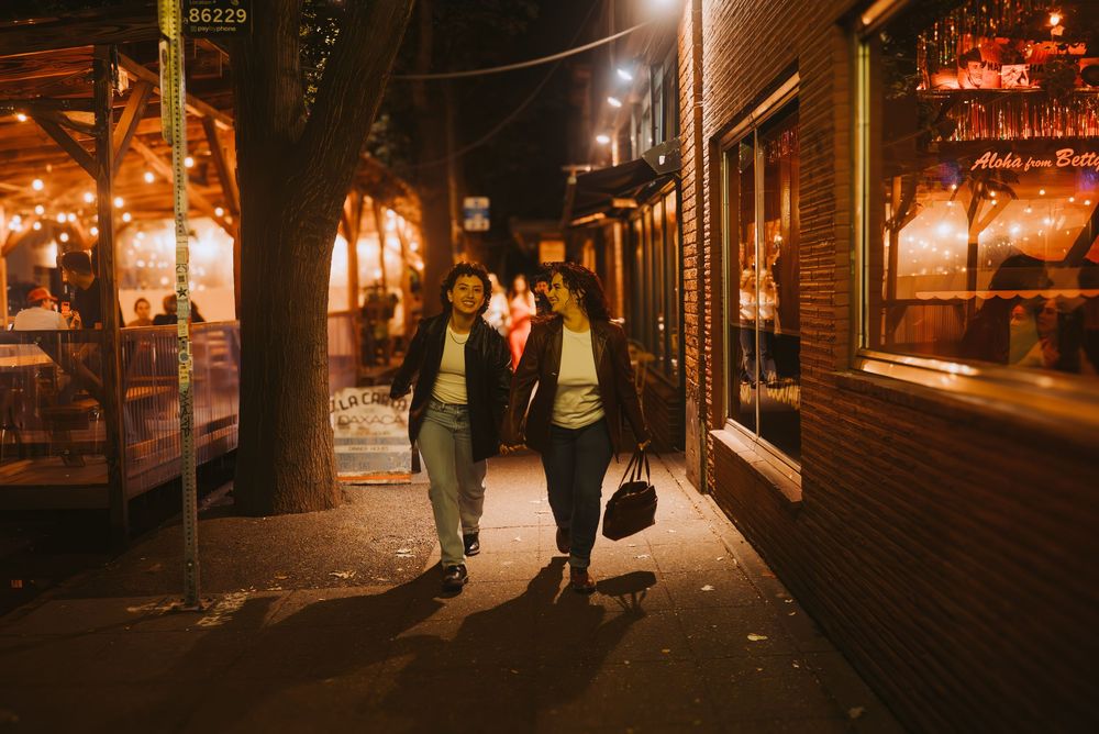 a lesbian couple walking together on dimly lit city streets at night in Seattle.