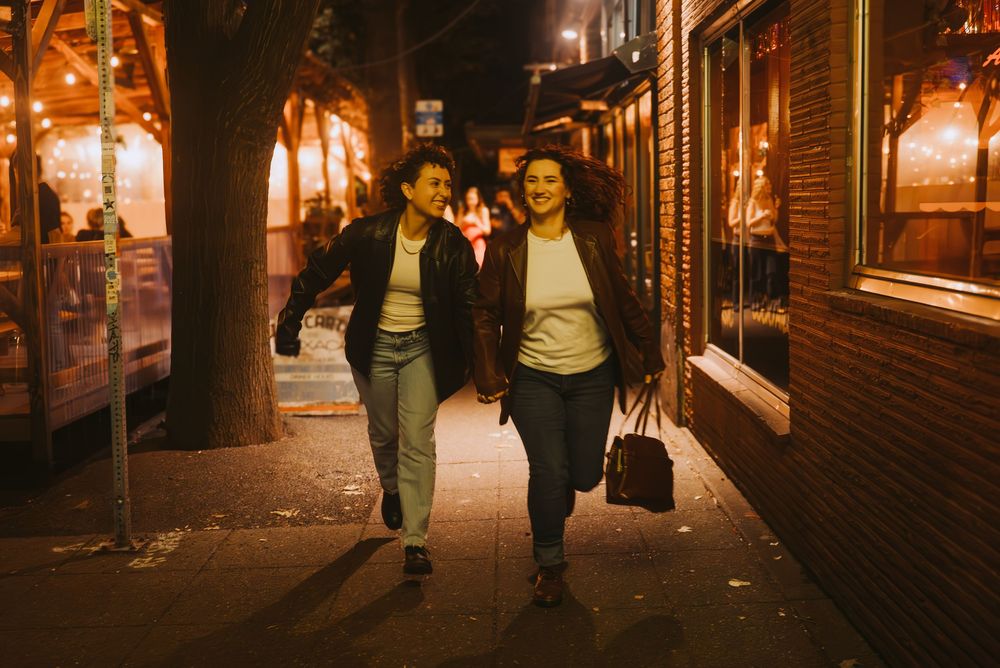 a lesbian couple walking together on dimly lit city streets at night in Seattle.