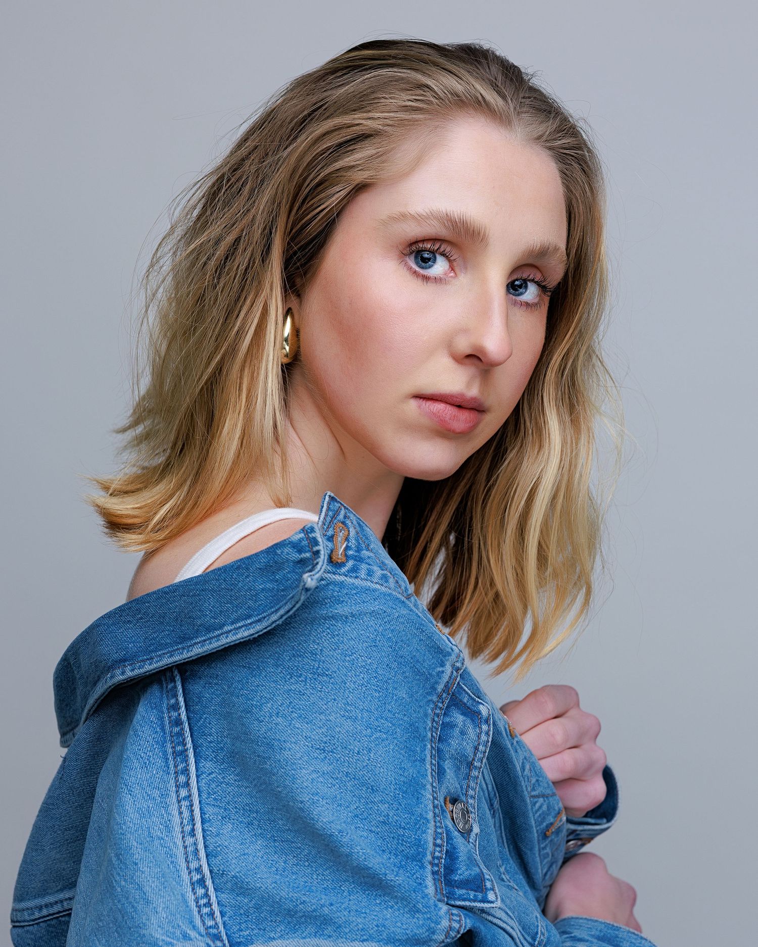 Model wearing a denim jacket poses against a gray backdrop in a series of artistic portraits.