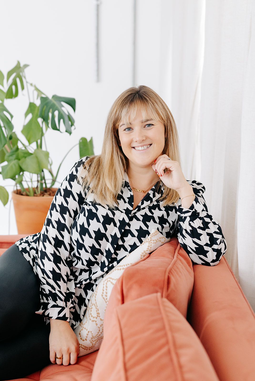 A series of lifestyle photos showing someone wearing a black and white houndstooth pattern top and coral coloured trousers.