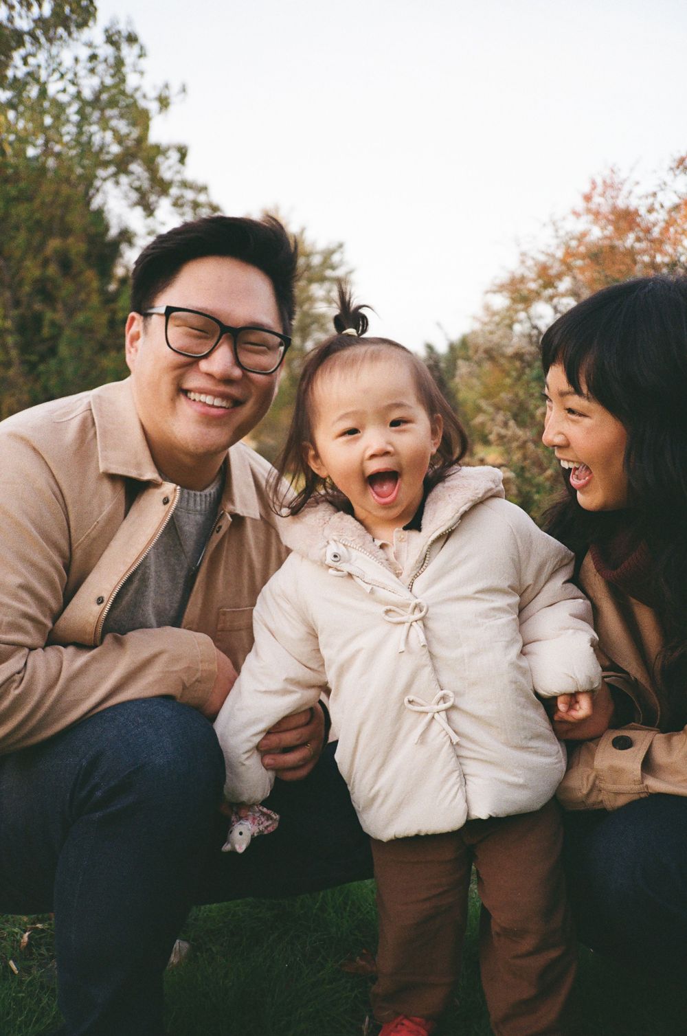 A joyful family sharing candid laughs together during an outdoor autumn photoshoot.