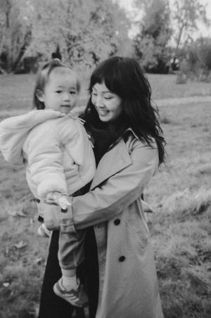 Black and white photos show a playful moment between a baby and caregiver in a winter coat outdoors.