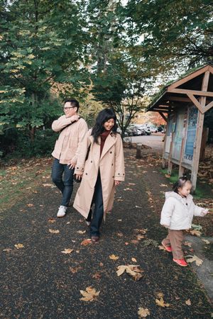 People playing and having fun with autumn leaves in a backyard garden setting.