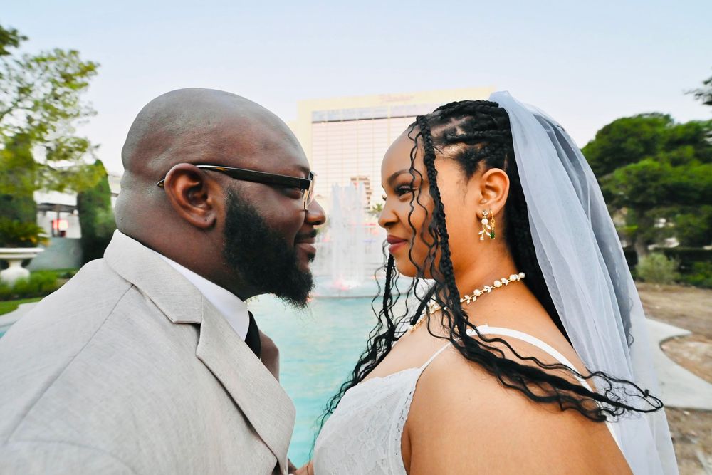 A bride and groom share an intimate moment gazing at each other during their wedding near a fountain.