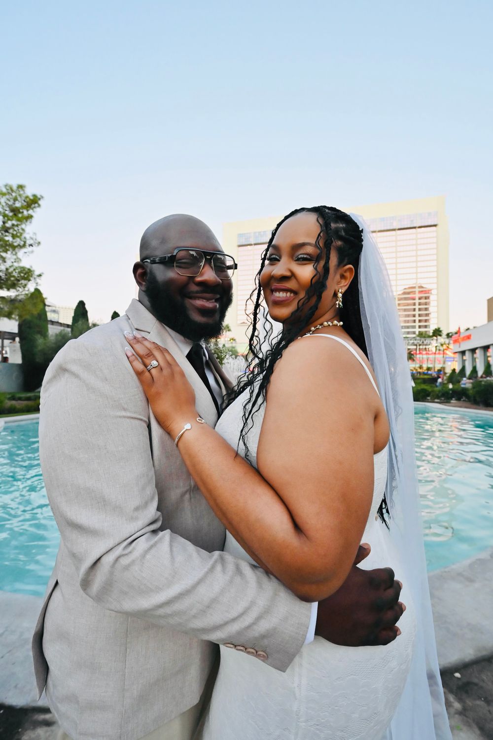 Happy bride and groom pose embracing by a pool in Las Vegas on their wedding day.