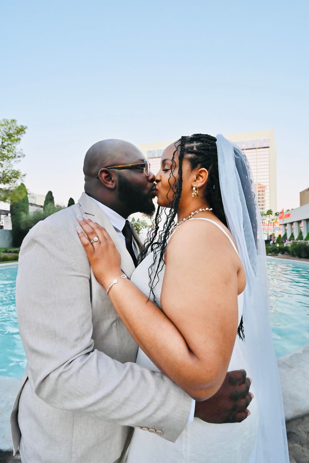A bride and groom share a passionate kiss while embracing by a Las Vegas pool on their wedding day.