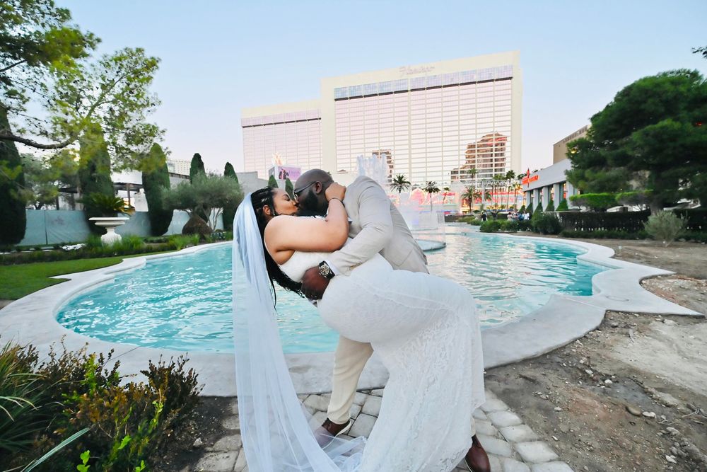 Newlywed couple sharing a romantic dip kiss in front of a pool at a Las Vegas wedding venue.