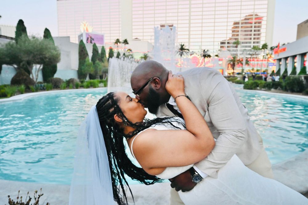 Couple sharing a passionate kiss in a dip pose by a fountain pool at a Las Vegas wedding.