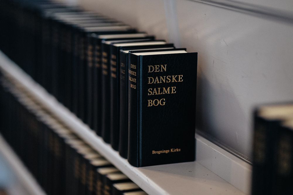 Black hardcover books with gold lettering arranged in a row on a wooden shelf.