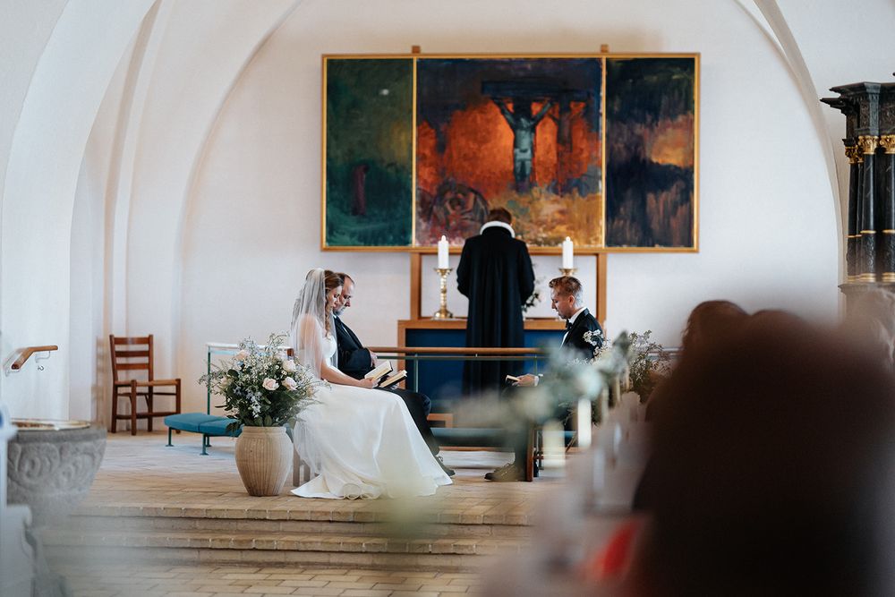 A couple shares a romantic dance in an elegant white ballroom with arched ceilings and artwork on the walls.