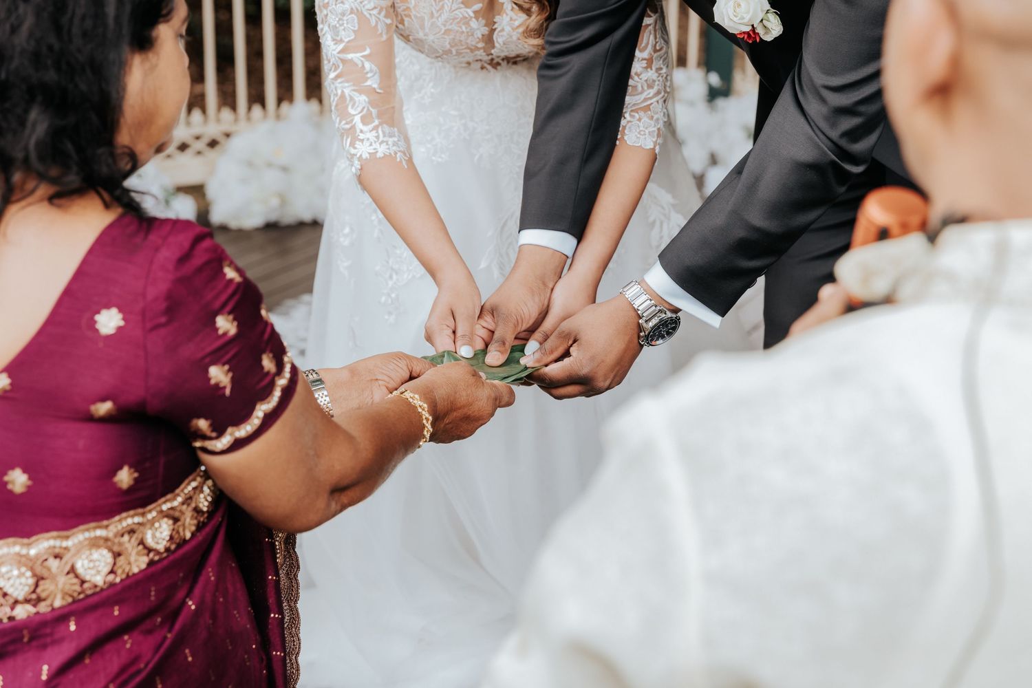 Close-up view of hands exchanging rings during a multicultural wedding ceremony with traditional Indian attire visible.