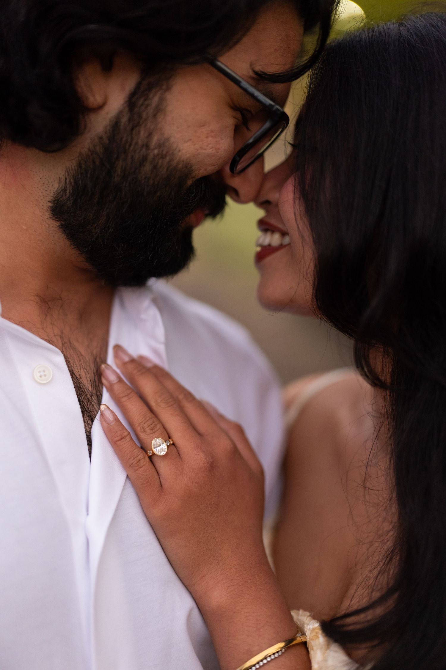 Close-up of a couple sharing a joyful moment with an engagement ring visible.