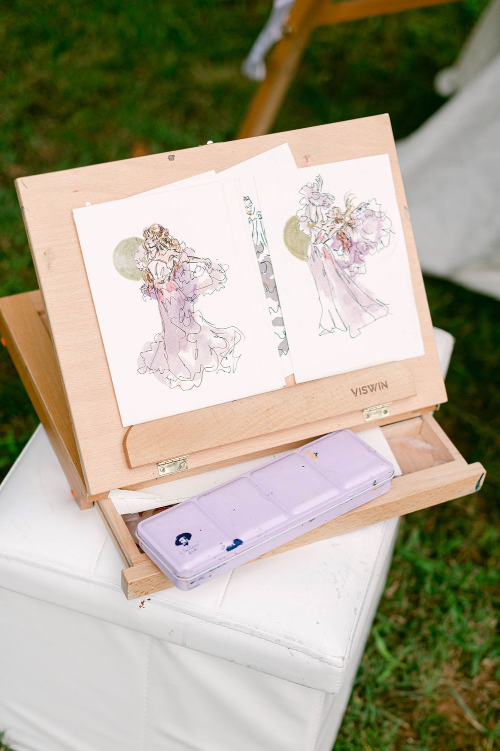 Delicate wedding sketches displayed on kraft paper with soft purple and pink watercolor details.