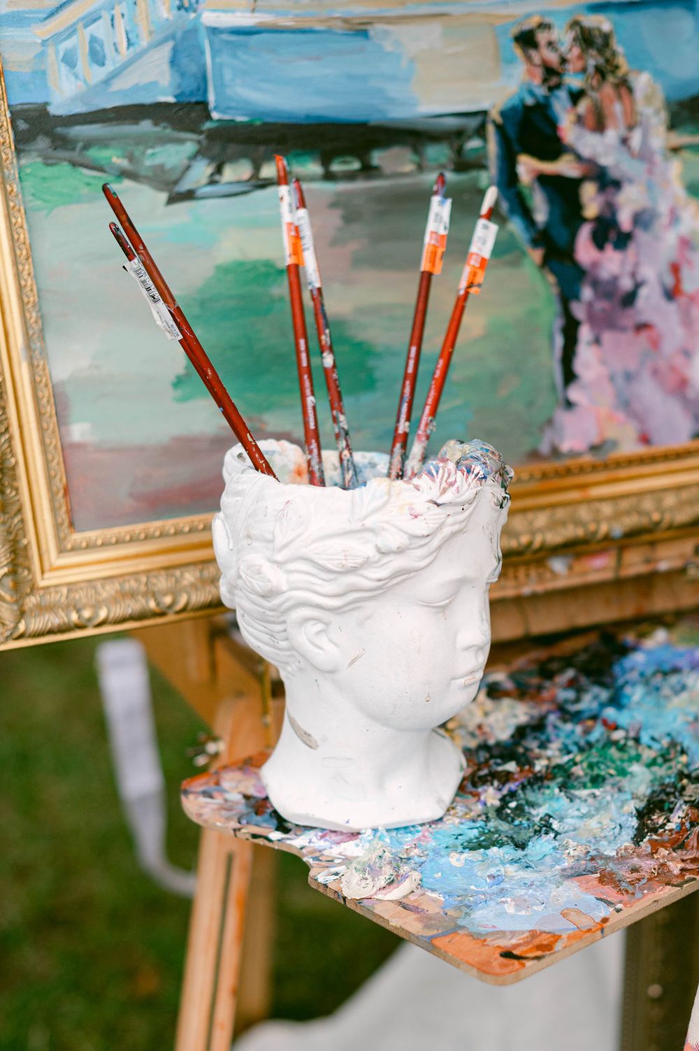 Artist's palette and brushes set up on an easel with white and blue paint swirls.