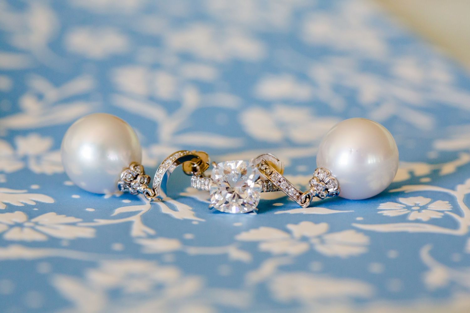 Pearl and crystal bridal jewelry set on blue patterned fabric.
