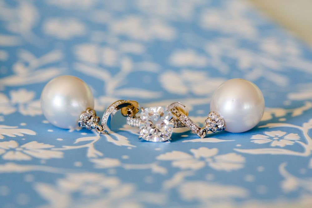 Pearl and crystal bridal jewelry set on blue patterned fabric.