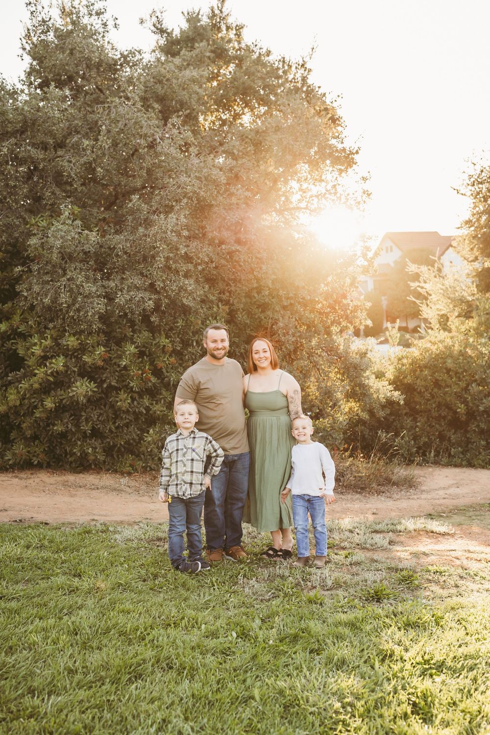 Beautiful sunset photo session in a grassy field with golden sunlight streaming through trees in the background.