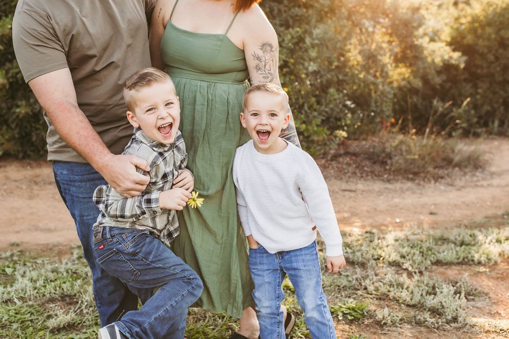 A family shares joyful moments together on a sunlit dirt path during a golden hour photoshoot.