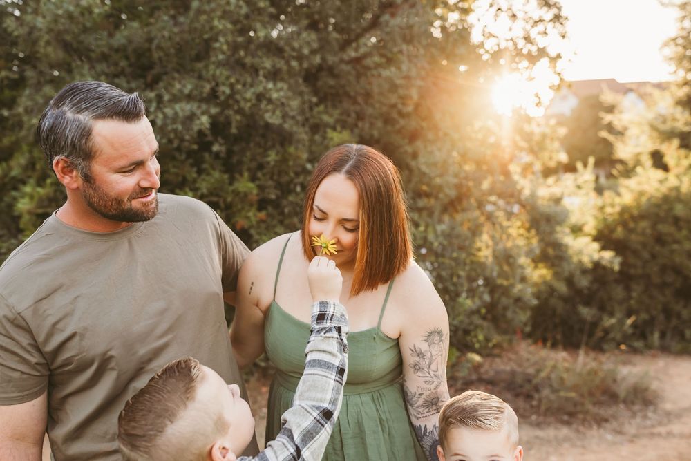 Family enjoys tender moments together in a sun-drenched outdoor setting during golden hour photography session.