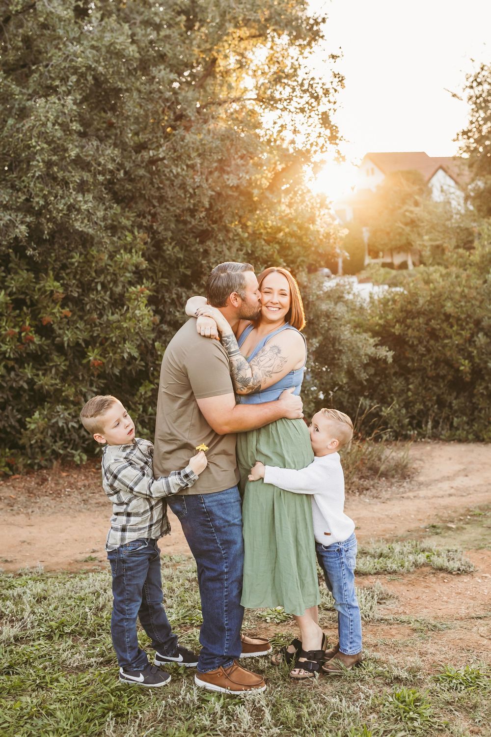A family shares tender moments together outdoors during golden hour sunset in a natural setting.
