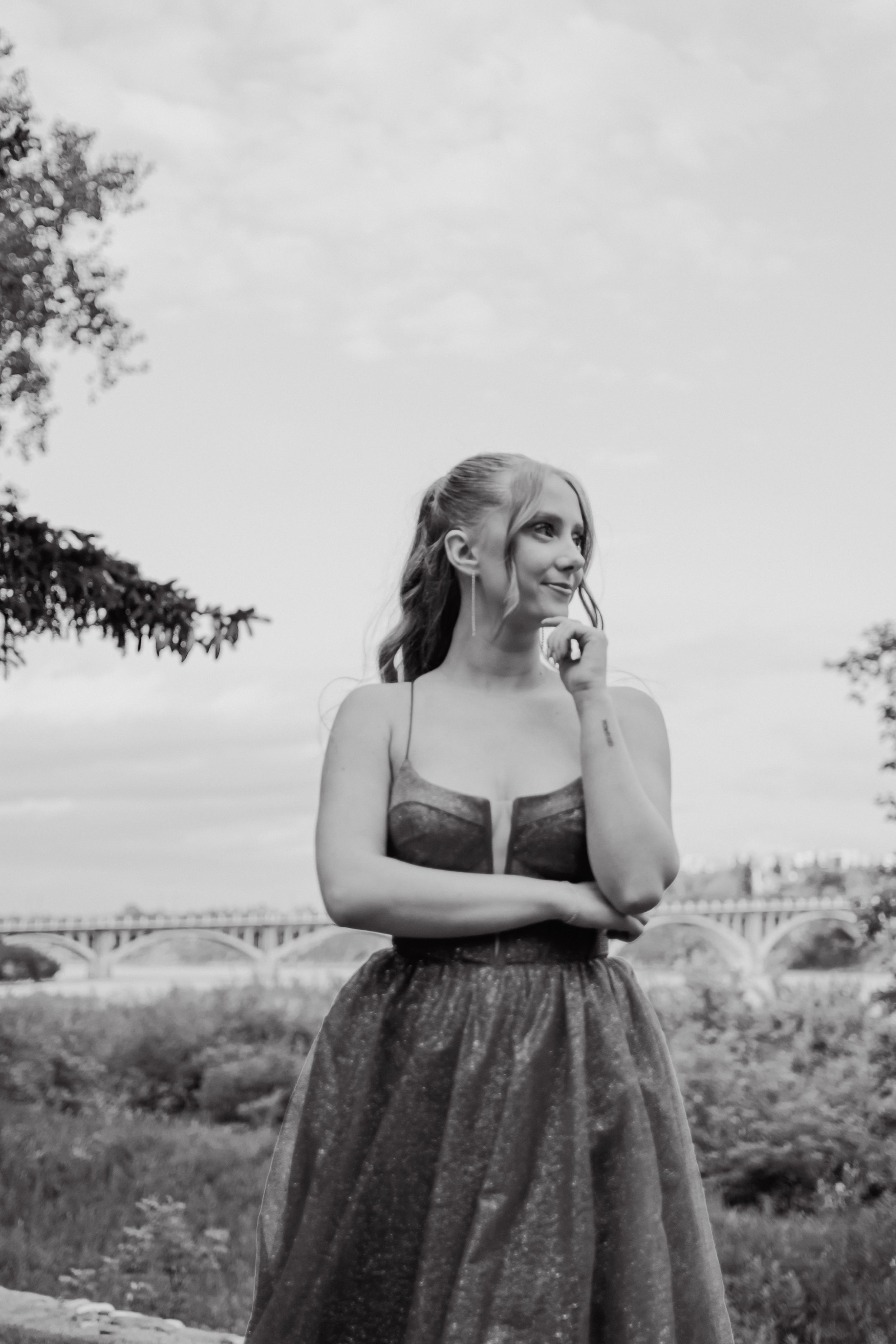 A series of black and white portraits showing a person in a sleeveless dress posing outdoors with a bridge in background.