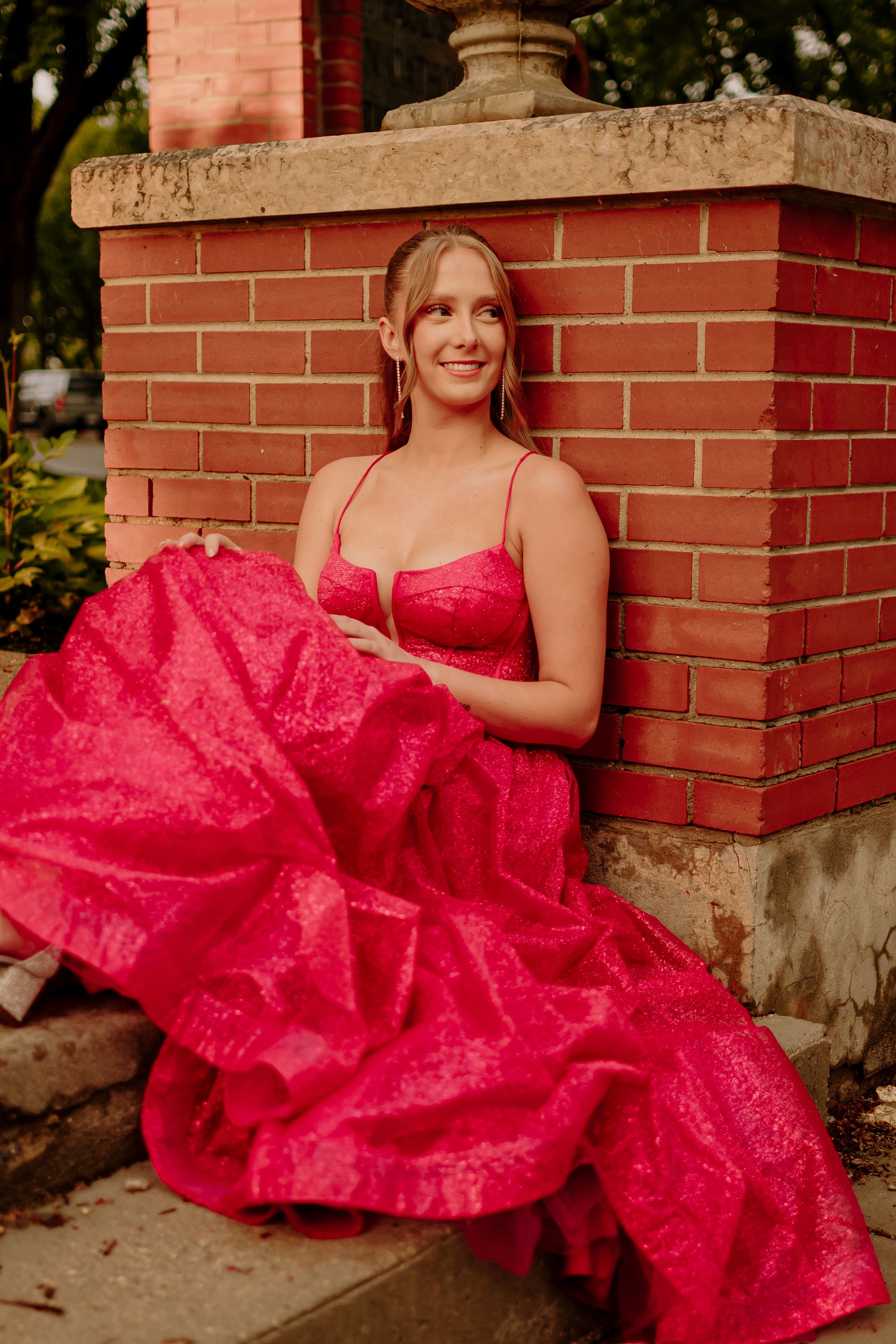 A sequence of shots featuring someone in a vibrant red formal dress posing against a brick wall outdoors.