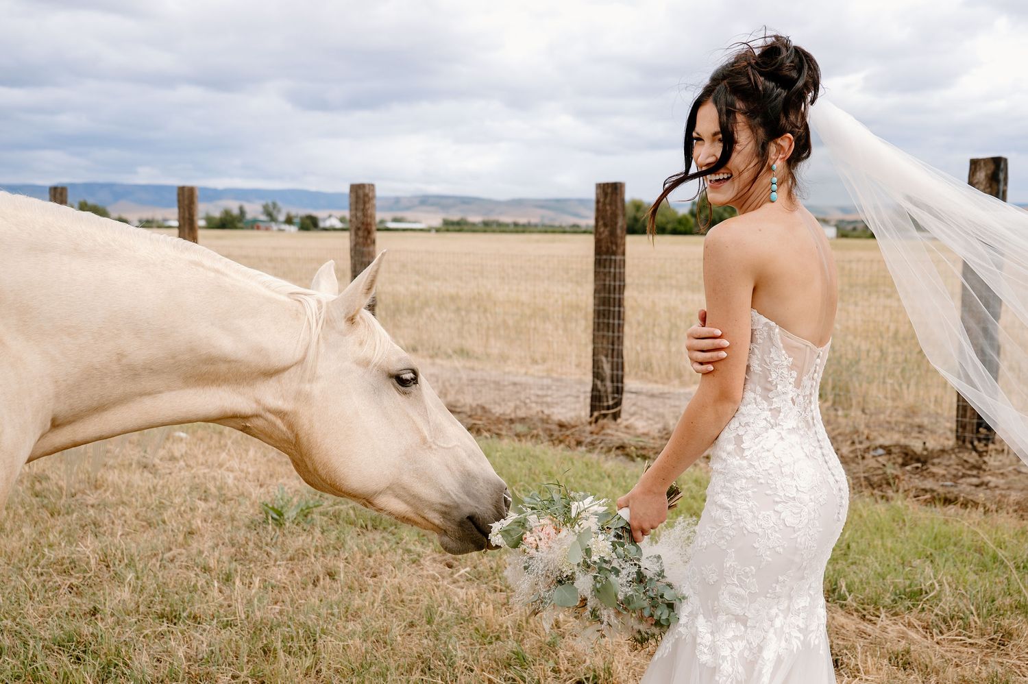 Western style bride stands with her bouquet next to one of the horses