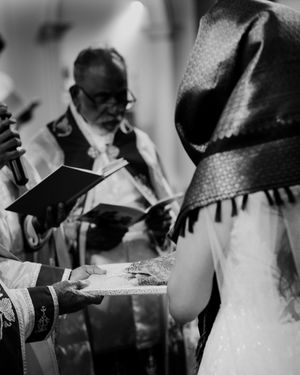 Black and white close-up of wedding ring exchange ceremony with officiant reading vows.