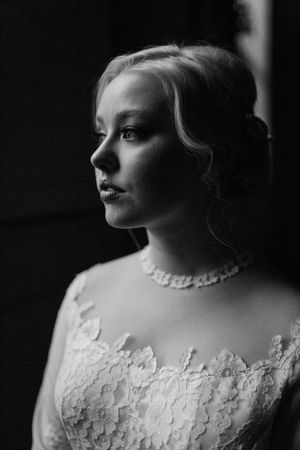 Elegant black and white bridal portrait of bride in lace gown with pearl necklace.