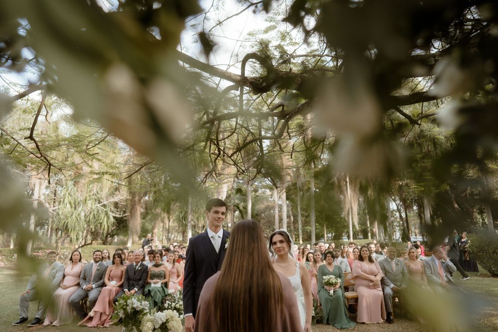 Wedding ceremony takes place in an outdoor garden setting with string lights hanging from trees and guests seated.
