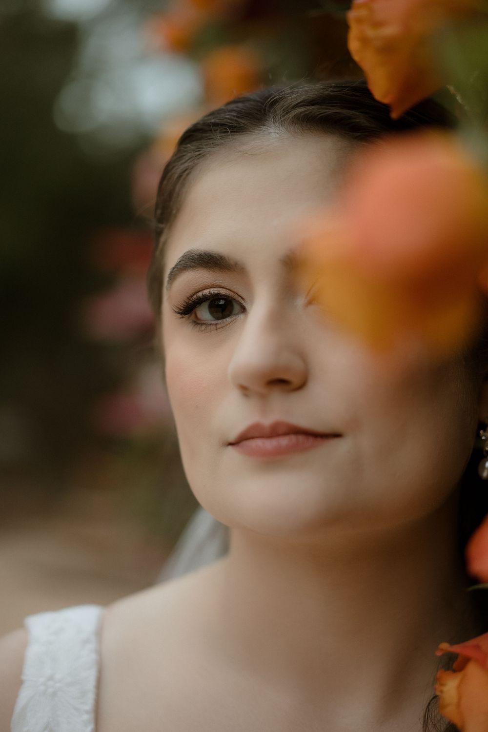 Close-up portrait with autumn leaves in soft focus creating a dreamy, romantic atmosphere.